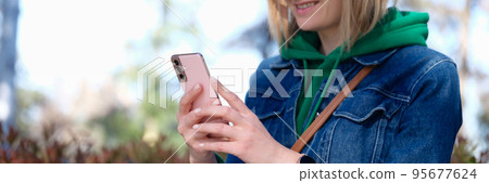 Smiling woman looks at phone on street Smiling woman looks at phone on street 95677624