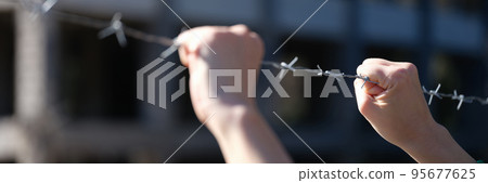 Hand behind barbed wire in prison or slavery closeup Hand behind barbed wire in prison or slavery closeup 95677625