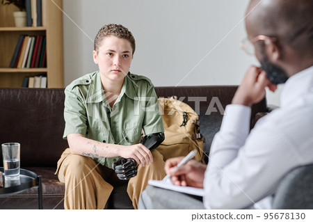 Young woman with disability visiting psychotherapist, she sitting on sofa and talking to him at office Young woman with disability visiting psychotherapist, she sitting on sofa and talking to him at office 95678130