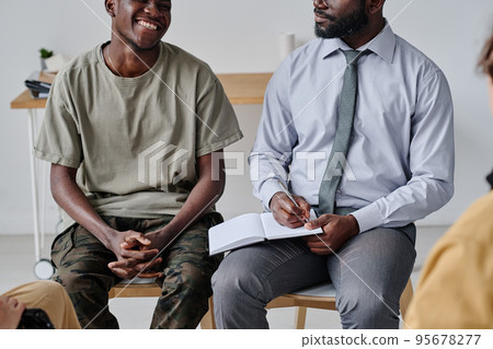 African psychiatrist talking to patient and making notes in notepad at psychology class African psychiatrist talking to patient and making notes in notepad at psychology class 95678277
