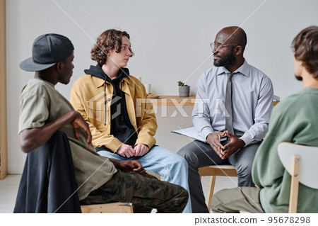 Group of students sitting on chairs and talking to their teacher during psychotherapy at class Group of students sitting on chairs and talking to their teacher during psychotherapy at class 95678298
