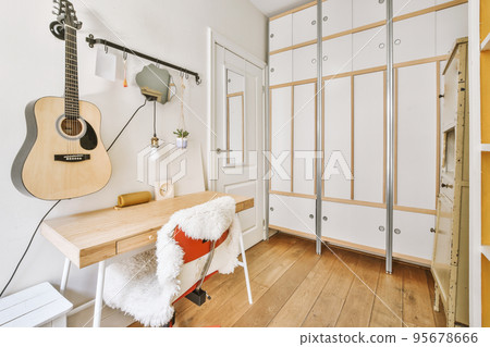 Home interior design of bedroom with bed and wooden wardrobe placed in corner near window in modern apartment 95678666