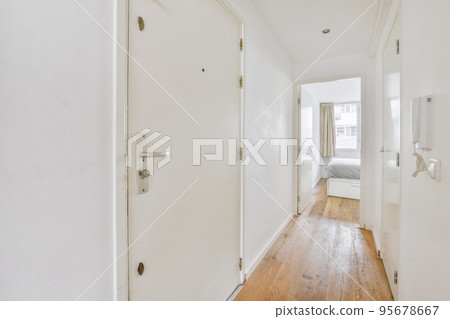 Light narrow hallway with many doors in white walls and glowing lamp over lumber floor 95678667