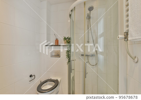 Tiled shower cabin with glass door located near sink and mirror in light restroom in contemporary apartment 95678678