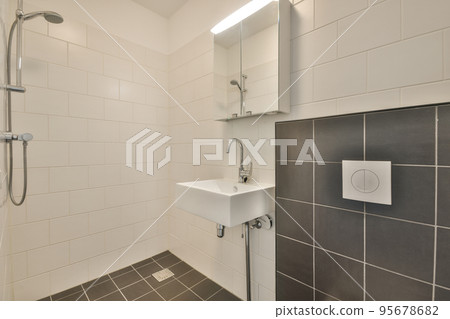 Wall hung toilet and small sink in corner in lavatory room with beige tile 95678682