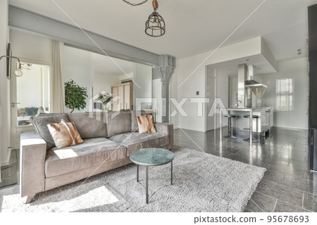 Table with chairs and flowers located near lounge area and kitchen in spacious room of contemporary apartment Table with chairs and flowers located near lounge area and kitchen in spacious room of contemporary apartment 95678693