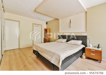 Home interior design of bedroom with bed and wooden wardrobe placed in corner near window in modern apartment 95678786