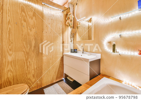 Flush toilet and shower cabin with glass partition and curtain located near sink and shelf with cosmetic products in washroom at home 95678798