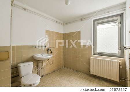 Flush toilet located between sink in small tiled bathroom 95678867