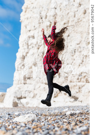 Little girl in red tartan dress, jumping at Hope Gap beach near Cuckmere Haven located between Seaford and Eastbourne in East Sussex, British south coast Little girl in red tartan dress, jumping at Hope Gap beach near Cuckmere Haven located between Seaford and Eastbourne in East Sussex, British south coast 95679042