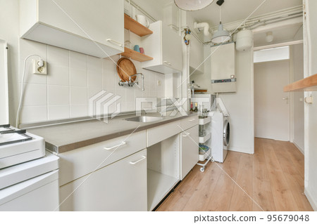 Assorted cookware and appliances placed on counters with white cabinets above in contemporary kitchen at home 95679048