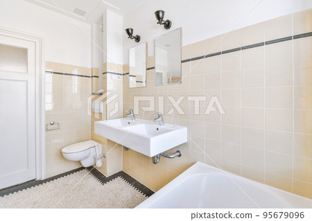 Spacious bathroom with stone sink and mirror on black and white colored tiled wall in expensive apartment 95679096