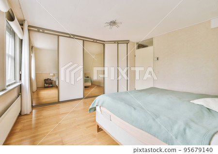 Comfortable bed placed near green wall in modern minimalist style mansard bedroom with windows Comfortable bed placed near green wall in modern minimalist style mansard bedroom with windows 95679140