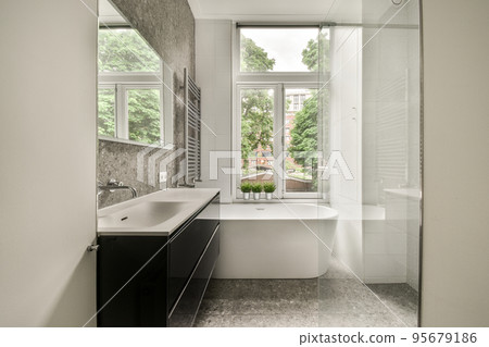 Modern home interior design of white bathroom with open bathtub and shower separated from toilet by partition wall Modern home interior design of white bathroom with open bathtub and shower separated from toilet by partition wall 95679186