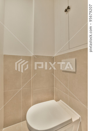 Interior of narrow restroom with sink and wall hung toilet with white walls and checkered floor Interior of narrow restroom with sink and wall hung toilet with white walls and checkered floor 95679207
