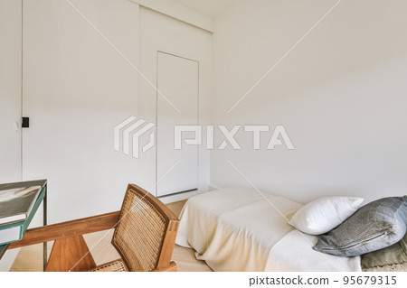 Home interior design of bedroom with bed and wooden wardrobe placed in corner near window in modern apartment 95679315