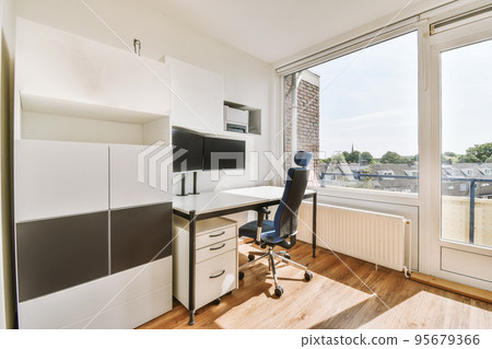 Comfortable chair placed near desk with computer monitors and whiteboard in light workplace in modern apartment 95679366