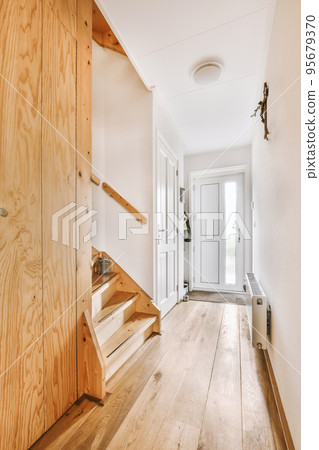 White hallway with wooden stairway leading to second floor of modern luxury apartment with minimalist interior design 95679370