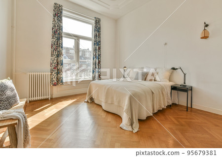 Comfortable bed with pillows and warm blanket located near window in stylish bedroom with green walls 95679381