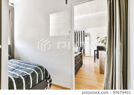 Home interior design of bedroom with bed and wooden wardrobe placed in corner near window in modern apartment Home interior design of bedroom with bed and wooden wardrobe placed in corner near window in modern apartment 95679401