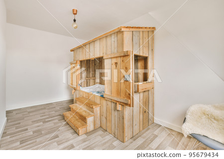 Stylish bed table with books and magazines near wooden bed under window Stylish bed table with books and magazines near wooden bed under window 95679434