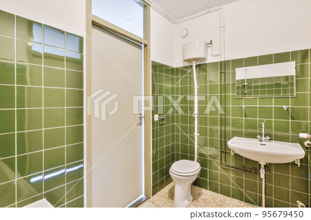 Bathtub with glass shower placed in corner near sink with toilet in small light bathroom with white tile walls Bathtub with glass shower placed in corner near sink with toilet in small light bathroom with white tile walls 95679450