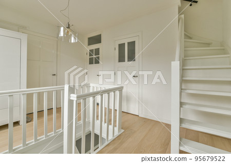 Interior of narrow corridor with telephone and radiator hanging on wall against stairway in daylight 95679522