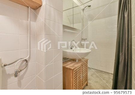 Wall hung toilet and small sink in corner in lavatory room with beige tile 95679573