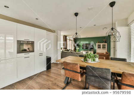 Interior of contemporary kitchen with stylish black and white cupboards and appliances near dining area in contemporary apartment 95679598