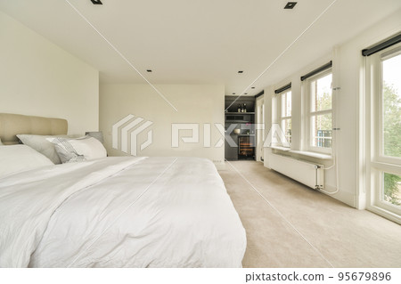 Comfortable bed located near balcony door with curtains in cozy light bedroom at home Comfortable bed located near balcony door with curtains in cozy light bedroom at home 95679896