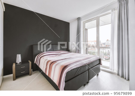 Home interior design of bedroom with bed and wooden wardrobe placed in corner near window in modern apartment Home interior design of bedroom with bed and wooden wardrobe placed in corner near window in modern apartment 95679899