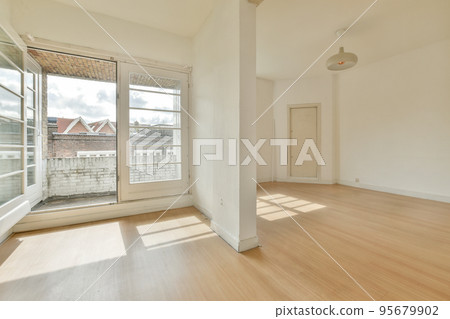 Interior of empty white room with large balcony windows with curtains and wooden parquet floor 95679902