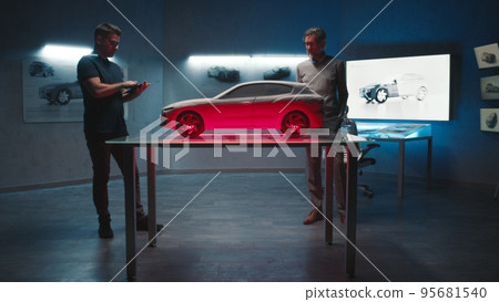 Automotive engineers examine the prototype car model in different shade of light Automotive engineers examine the prototype car model in different shade of light 95681540
