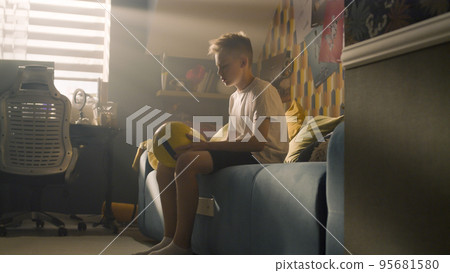 Young boy plays football alone in his bedroom and performs tricks with the ball Young boy plays football alone in his bedroom and performs tricks with the ball 95681580
