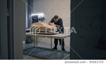 Male designer creates prototype model of a car made of clay using sculpting tool 95681724