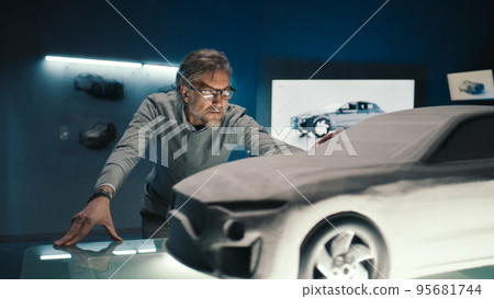 Automotive engineer touches the model of the prototype car to make design change 95681744