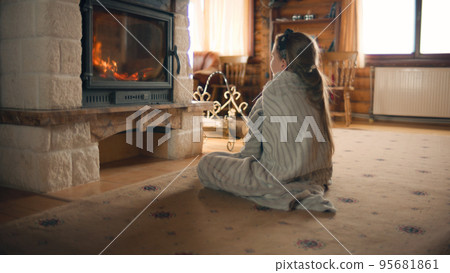 Young girl sitting by the fireplace 95681861