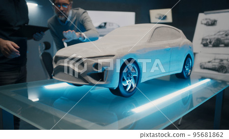 Experienced designers discuss the car design infront of a rake sculpt prototype 95681862
