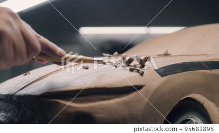 Man with rake working on clay car model 95681898