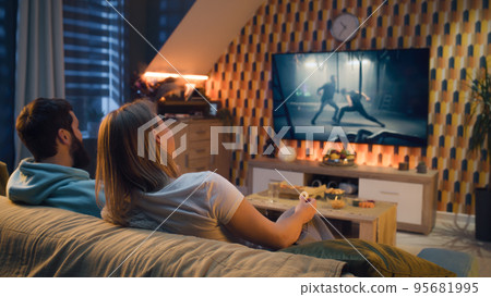 Couple watching action movie on TV at home 95681995