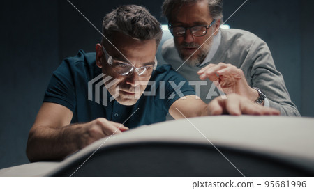 Design engineer with safety goggles makes design corrections in sculpture of car Design engineer with safety goggles makes design corrections in sculpture of car 95681996