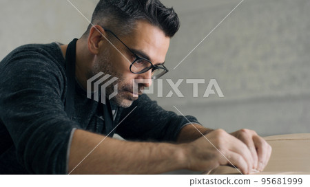 Ceramist uses sculpting tool to create the design details on sculpture of a car 95681999
