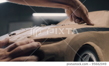 Man working on clay model of electric car 95682049