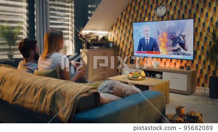 Couple watching TV news about war in Ukraine Couple watching TV news about war in Ukraine 95682089
