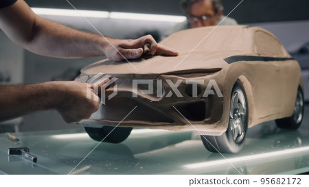 Male designers creating plasticine car model Male designers creating plasticine car model 95682172
