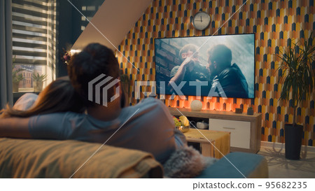 Couple on sofa watching action movie Couple on sofa watching action movie 95682235