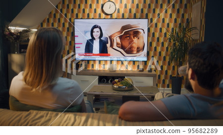 Couple watching news about space mission Couple watching news about space mission 95682289