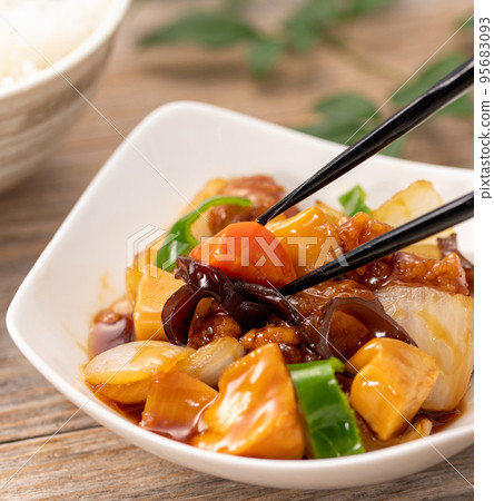 Sweet and sour pork (subuta) close-up, picking up with chopsticks 95683093