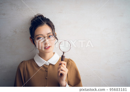 Conceptual photo of a woman looking through a magnifying glass Conceptual photo of a woman looking through a magnifying glass 95683181