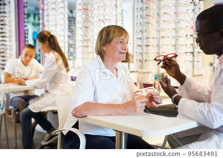 Ophthalmologist helping mature woman to choose glasses Ophthalmologist helping mature woman to choose glasses 95683491
